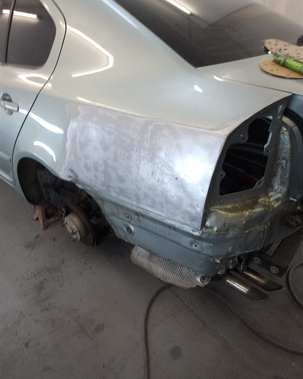 A rear quarter panel taken back to bare metal for welding and rust repair