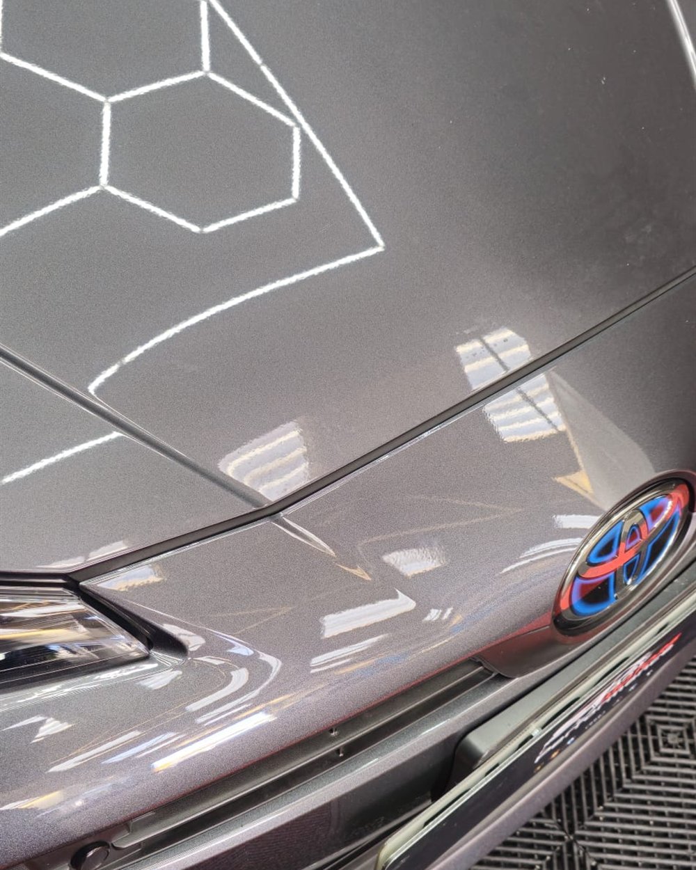 Deep gloss on a freshly polished bonnet reflecting the workshop ceiling lights
