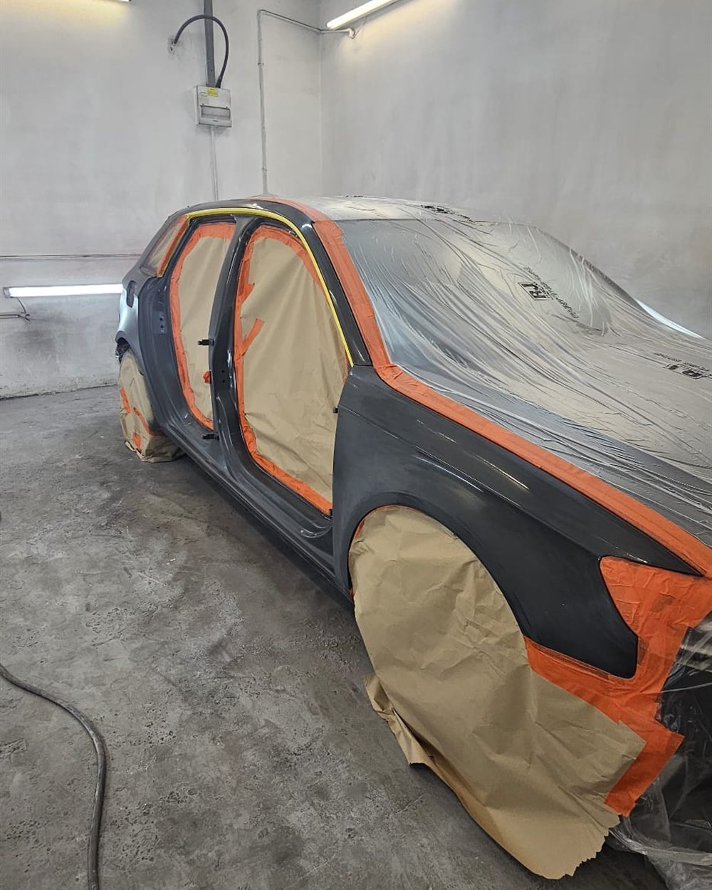 A car masked in paper and tape for a panel respray